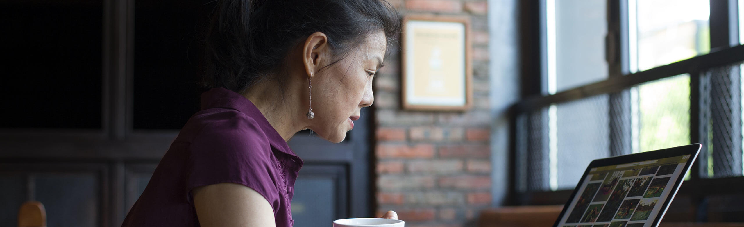 Imagen de una mujer tomando un café mientras trabaja con un portátil.