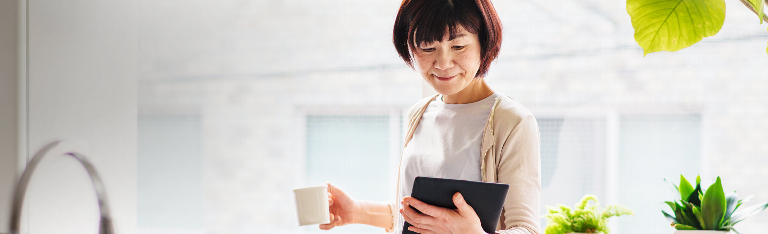 Imagen de una mujer con una taza de café y usando la tableta.